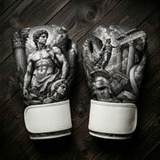 Black and white boxing gloves featuring a classical Greek god statue, ancient stone pillars, a winged goddess soaring over a temple, and a warrior helmet art design for combat sports training.