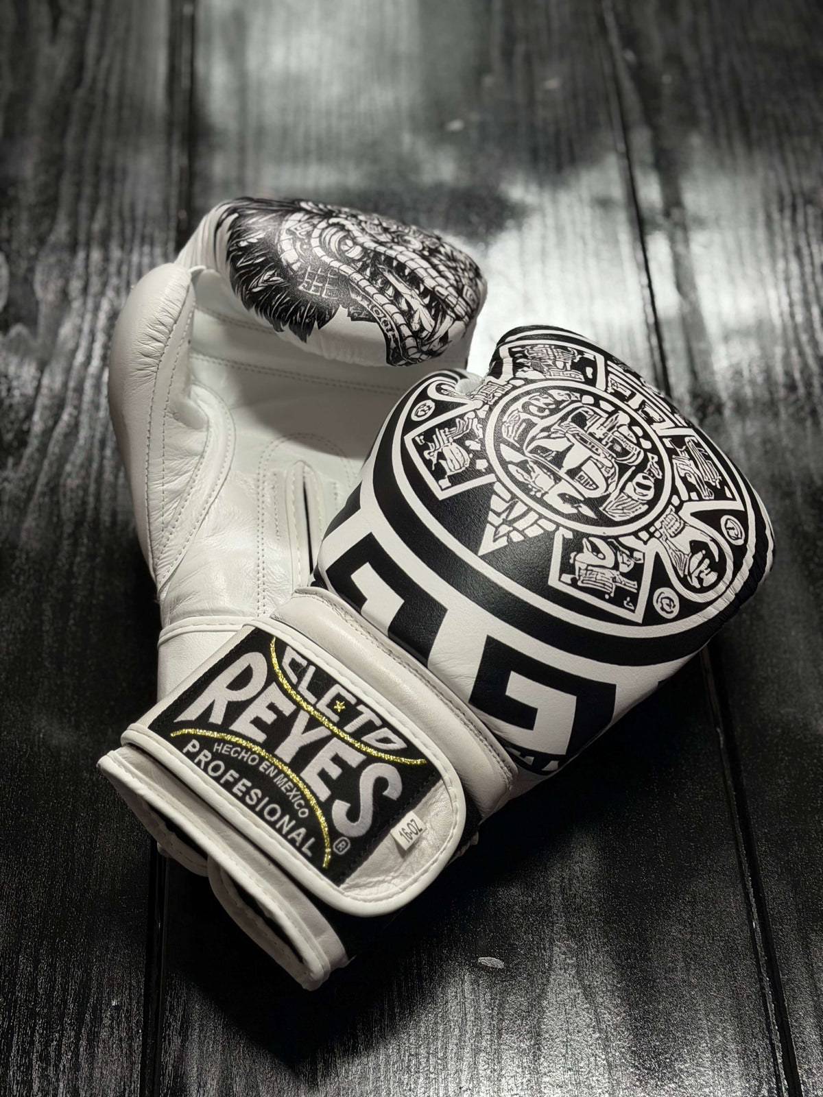 Cleto Reyes Professional boxing gloves in white featuring an intricate black Aztec calendar and tribal art design layout.