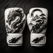 White and black boxing gloves featuring a traditional Japanese dragon over ocean waves and a scenic mountain landscape with an Enso circle and bonsai tree ink wash design for combat sports training.