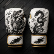 White and black boxing gloves featuring a fierce tiger with bamboo and a traditional mythical dragon ink wash art design for combat sports training.