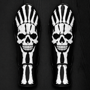 Fiest Gloves custom black-and-white kickboxing and MMA shin guards featuring a bold skeletal design with a realistic human skull graphic and matching bone structures