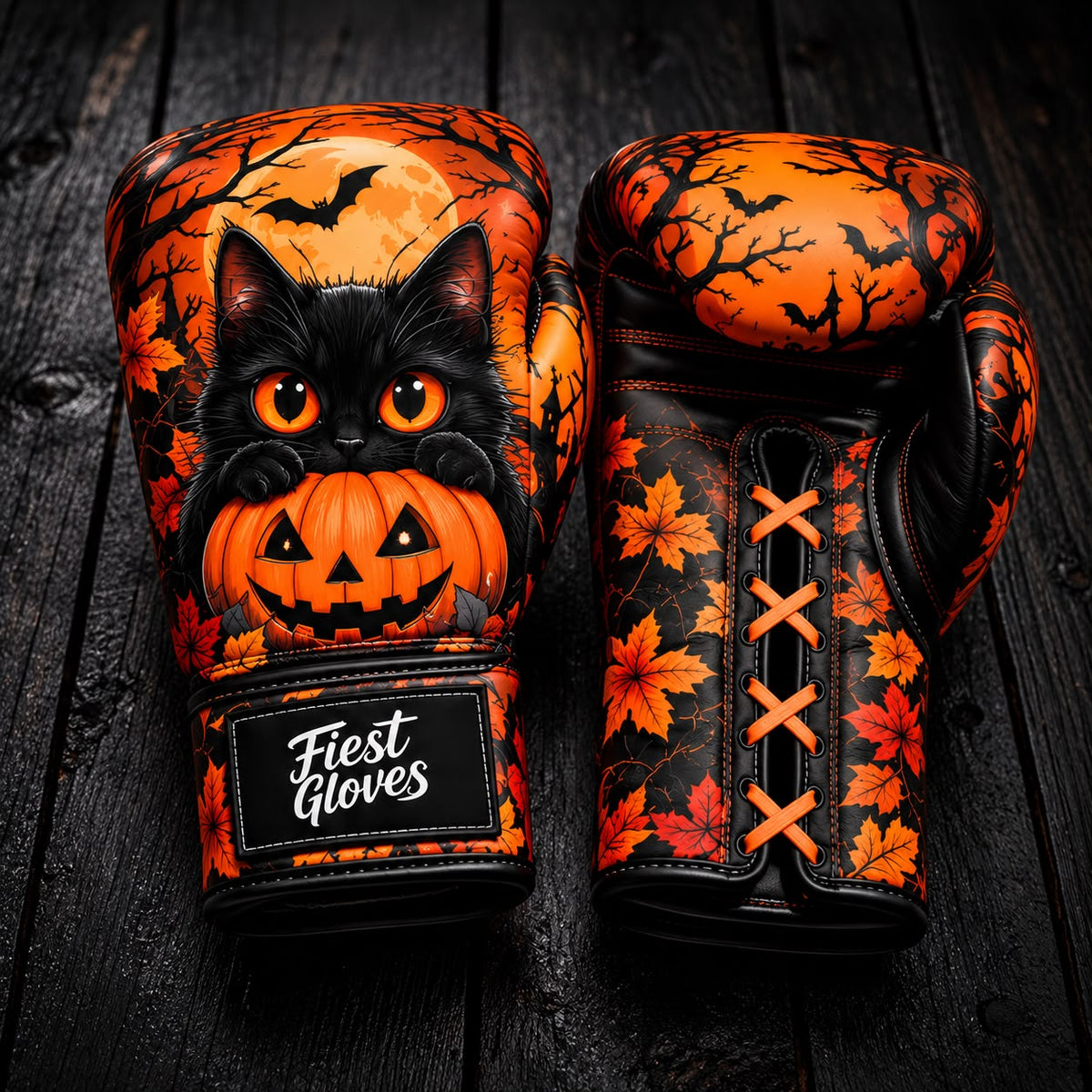 Fiest Gloves Halloween edition boxing gloves featuring a cute black cat holding a Jack-o'-lantern pumpkin, full moon, flying bats, and autumn leaf pattern on a dark wood background.   
