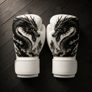White Fiest Gloves boxing gloves featuring a detailed black ink dragon design resting on a dark wooden surface.