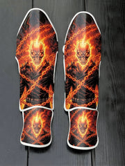 Custom Ghost Rider superhero design with blazing skull, leather jacket, crossed hellfire chains, and fiery orange background soccer shin guards displayed on a dark surface.