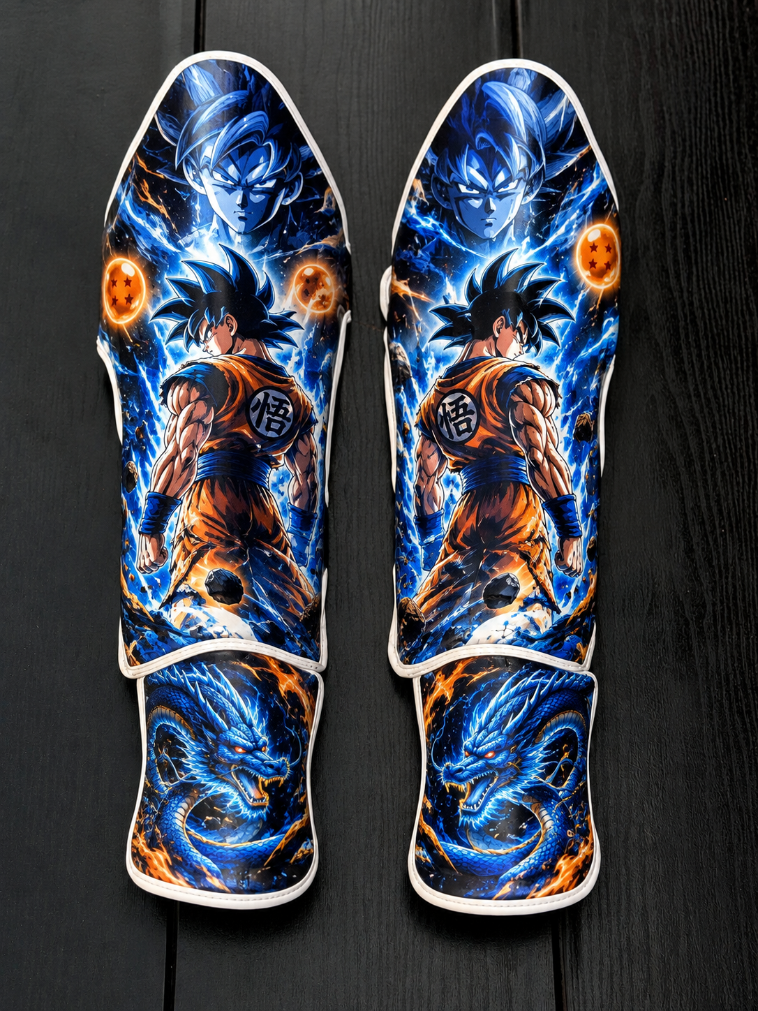 Custom Goku Ultra Instinct and Blue Dragon anime soccer shin guards laid flat on a dark wooden background.