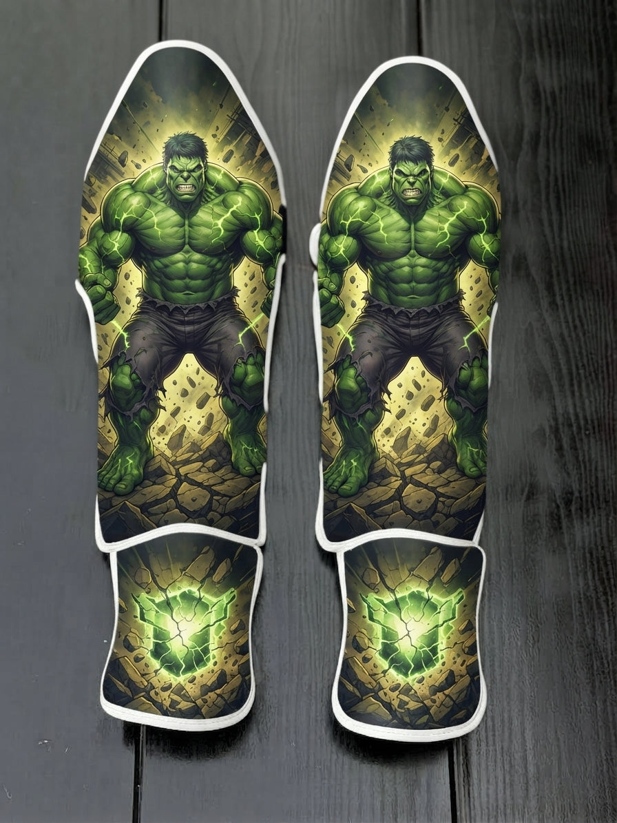 Custom Hulk superhero design with muscular green physique, gamma energy veins, destroyed ground background, and glowing cracked green stone emblem soccer shin guards displayed on a dark surface.