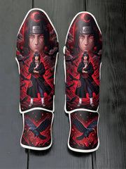 Custom Itachi Uchiha anime design with Sharingan eyes, Akatsuki cloak, and soaring black crows against a red background soccer shin guards displayed on a dark surface.