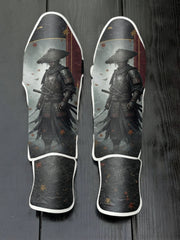 Custom Japanese samurai design with traditional ronin hat, dark armor, katana swords, falling maple leaves, and wave pattern background soccer shin guards displayed on a dark surface.