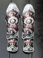 Custom Monkey D. Luffy Gear 5 awakening anime design with white hair, clouds, and straw hat skull logo soccer shin guards displayed on a dark surface.