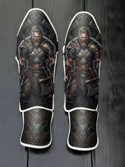 Custom Viking warrior design with fur mantle, roaring expression, axes, intricate Norse runic patterns, and dark metallic background soccer shin guards displayed on a dark surface.