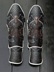 Custom Viking warrior design with horned or metal helm, fur armor, battle axes, intricate Celtic knotwork background with ravens, and Norse shield emblem soccer shin guards displayed on a dark surface.