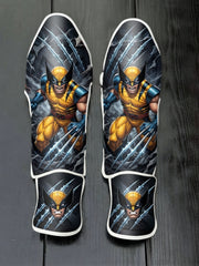 Custom Wolverine superhero design with classic yellow and blue suit, adamantium claws slashing background, and masked portrait soccer shin guards displayed on a dark surface.